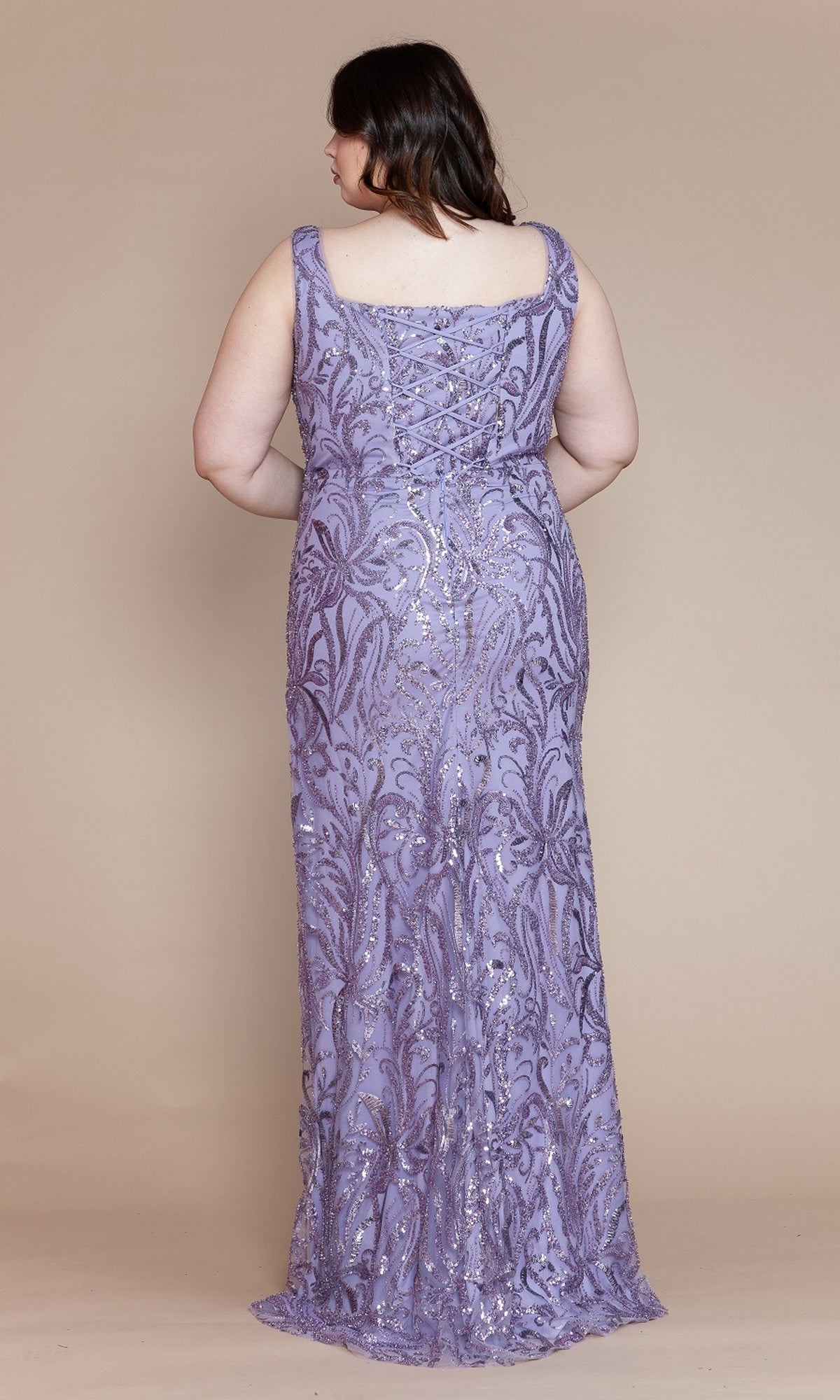 A woman faces away, wearing the Glitter-Print Long Plus-Size Prom Dress W1140, a sleeveless, floor-length lavender gown with sequin and bead details, set against a plain beige background.